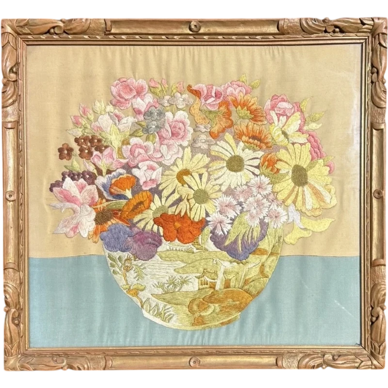 Framed panel featuring a vase of flowers embroidered on fabric.