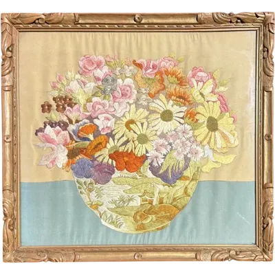 Framed panel featuring a vase of flowers embroidered on fabric.