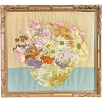 Framed panel featuring a vase of flowers embroidered on fabric.