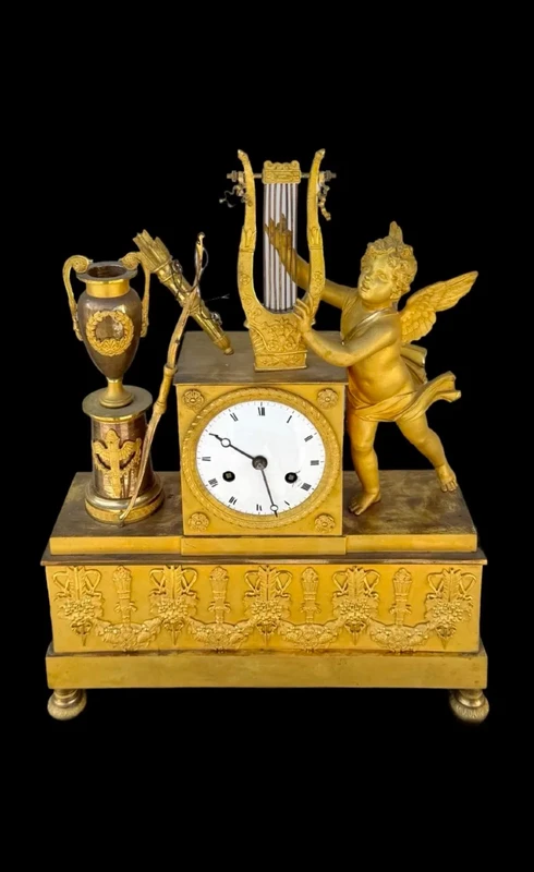 A clock made of mercury-gilded bronze depicting Cupid playing the lyre.
