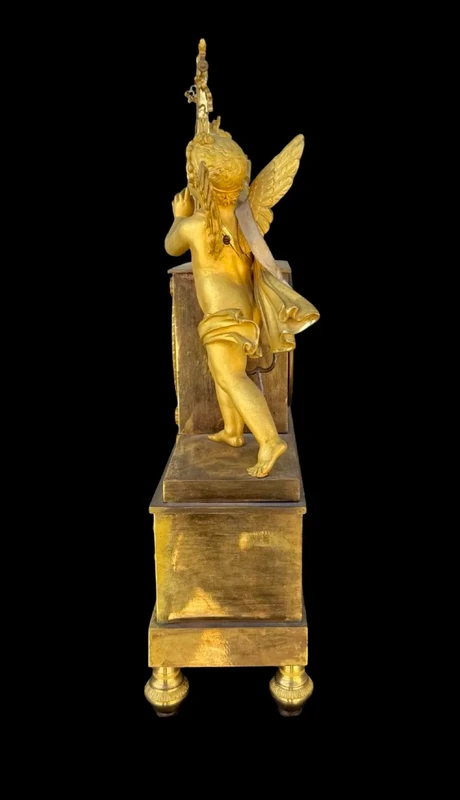 A clock made of mercury-gilded bronze depicting Cupid playing the lyre.