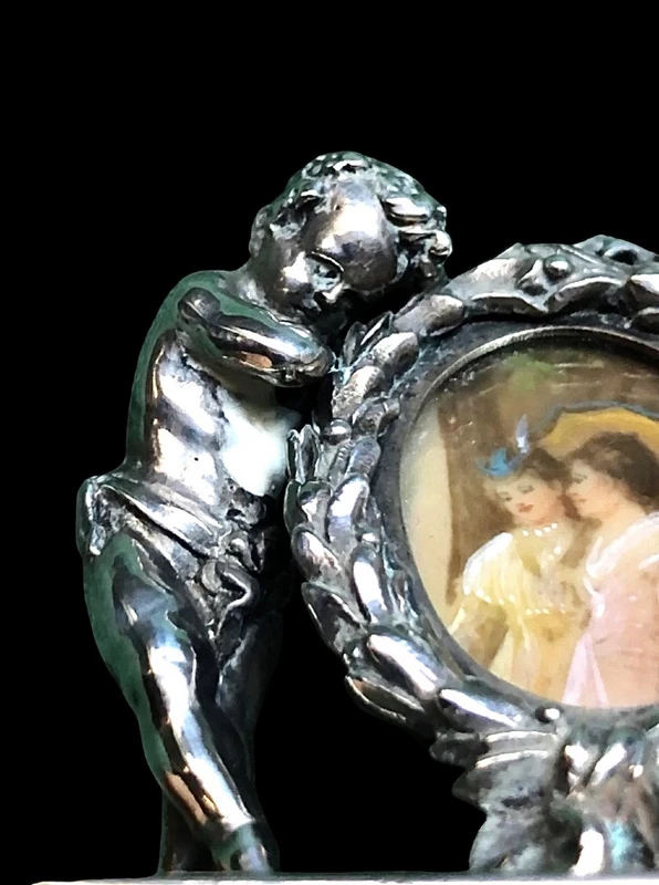 Solid silver paperweight featuring two cherubs holding up a portrait frame