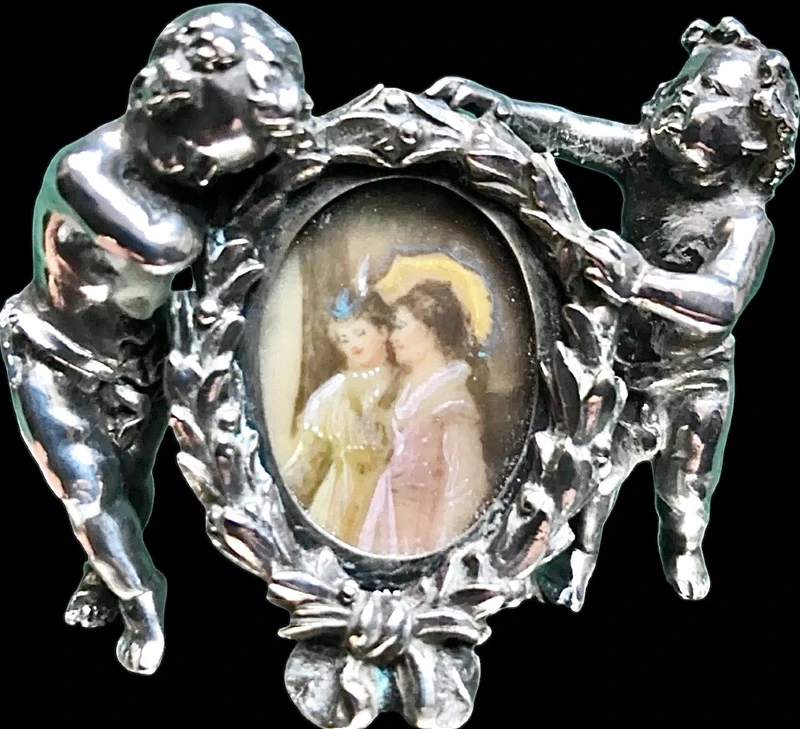 Solid silver paperweight featuring two cherubs holding up a portrait frame