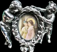 Solid silver paperweight featuring two cherubs holding up a portrait frame
