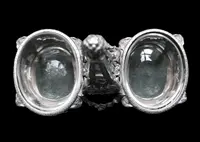 Double salt shaker set made of solid silver with glass compartments.