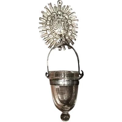 Basket-shaped holy water font in embossed silver with ray motifs and a Marian symbol