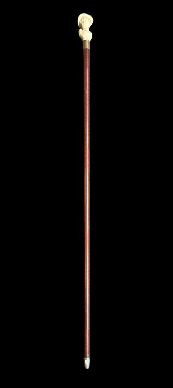 A walking stick with an ivory knob depicting a woman's bust wearing a hat.
