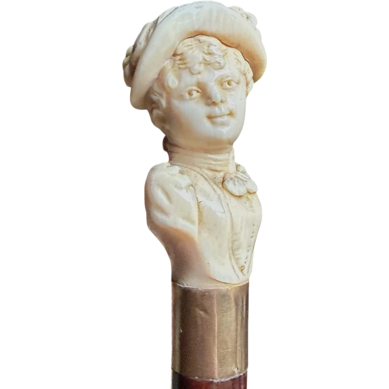 A walking stick with an ivory knob depicting a woman's bust wearing a hat.