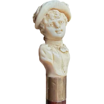 A walking stick with an ivory knob depicting a woman's bust wearing a hat.