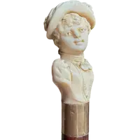 A walking stick with an ivory knob depicting a woman's bust wearing a hat.