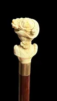 A walking stick with an ivory knob depicting a woman's bust wearing a hat.