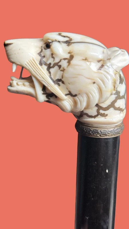 A walking stick with an ivory knob shaped like a tiger's head.