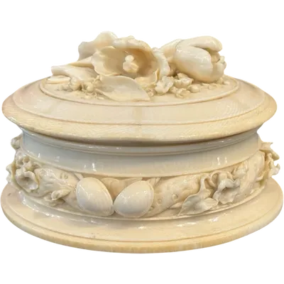 An oval-shaped ivory box decorated with bas-relief plant and floral motifs.