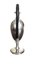 A silver coffee pot with a pear-shaped body on a circular base adorned with lanceolate leaves.