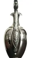 A silver coffee pot with a pear-shaped body on a circular base adorned with lanceolate leaves.