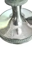 A silver coffee pot with a pear-shaped body on a circular base adorned with lanceolate leaves.