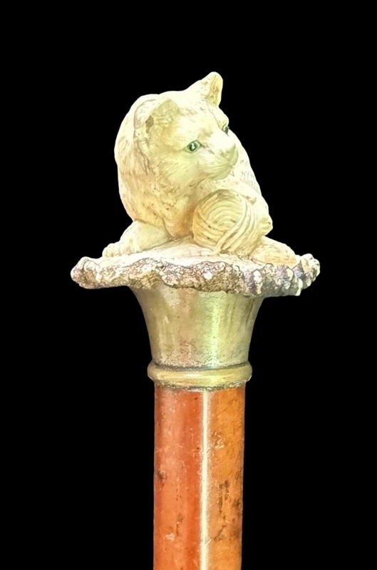 Walking stick with a deer antler knob depicting a cat playing with a ball of yarn.
