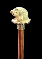 Walking stick with a deer antler knob depicting a cat playing with a ball of yarn.