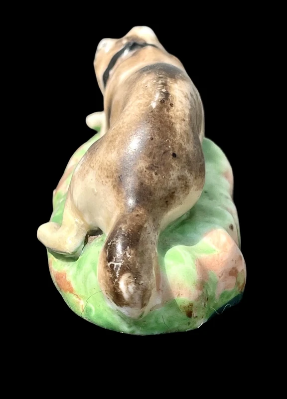 Sculpture en porcelaine polychrome représentant un chien allongé sur un tapis d'herbe. Jacob Petit