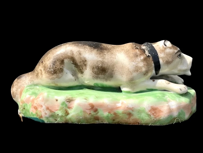Sculpture en porcelaine polychrome représentant un chien allongé sur un tapis d'herbe. Jacob Petit