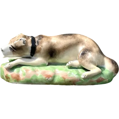 Polychrome porcelain sculpture depicting a dog lying on a grassy slope. Jacob Petit
