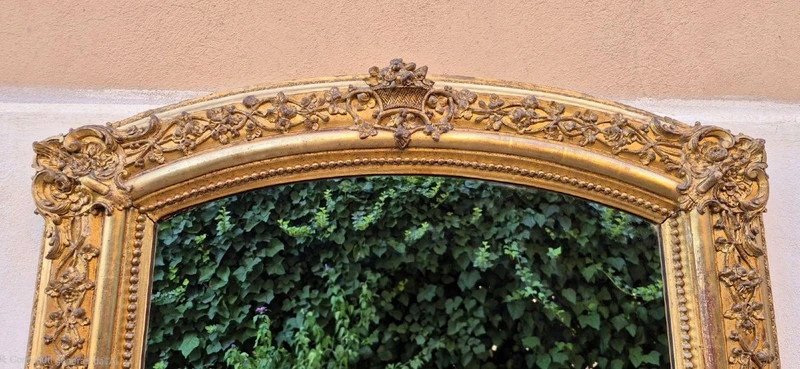 Antique gilded 19th-century mirror with an arched cornice