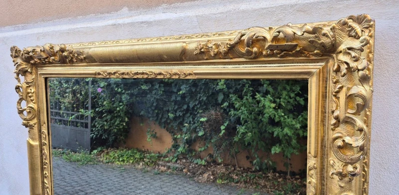 An antique Emilian mirror with openwork design, made of gilded wood, dating from the mid-19th century.