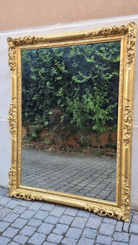 An antique Emilian mirror with openwork design, made of gilded wood, dating from the mid-19th century.