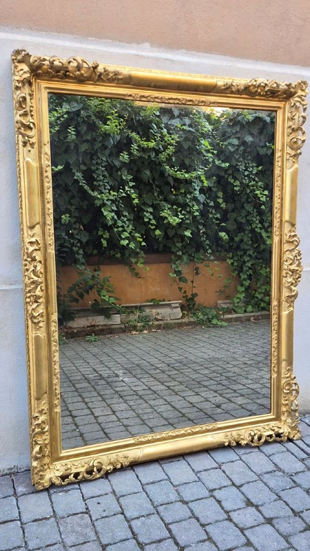 An antique Emilian mirror with openwork design, made of gilded wood, dating from the mid-19th century.