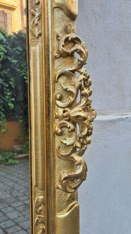 An antique Emilian mirror with openwork design, made of gilded wood, dating from the mid-19th century.