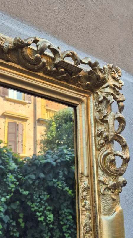 An antique Emilian mirror with openwork design, made of gilded wood, dating from the mid-19th century.